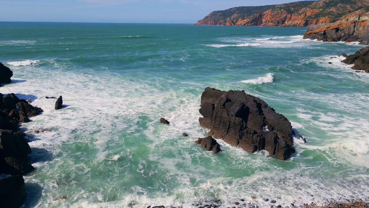 波涛汹涌的海浪在多石的海岸线上缓慢翻滚。海水冲刷海岸视频素材