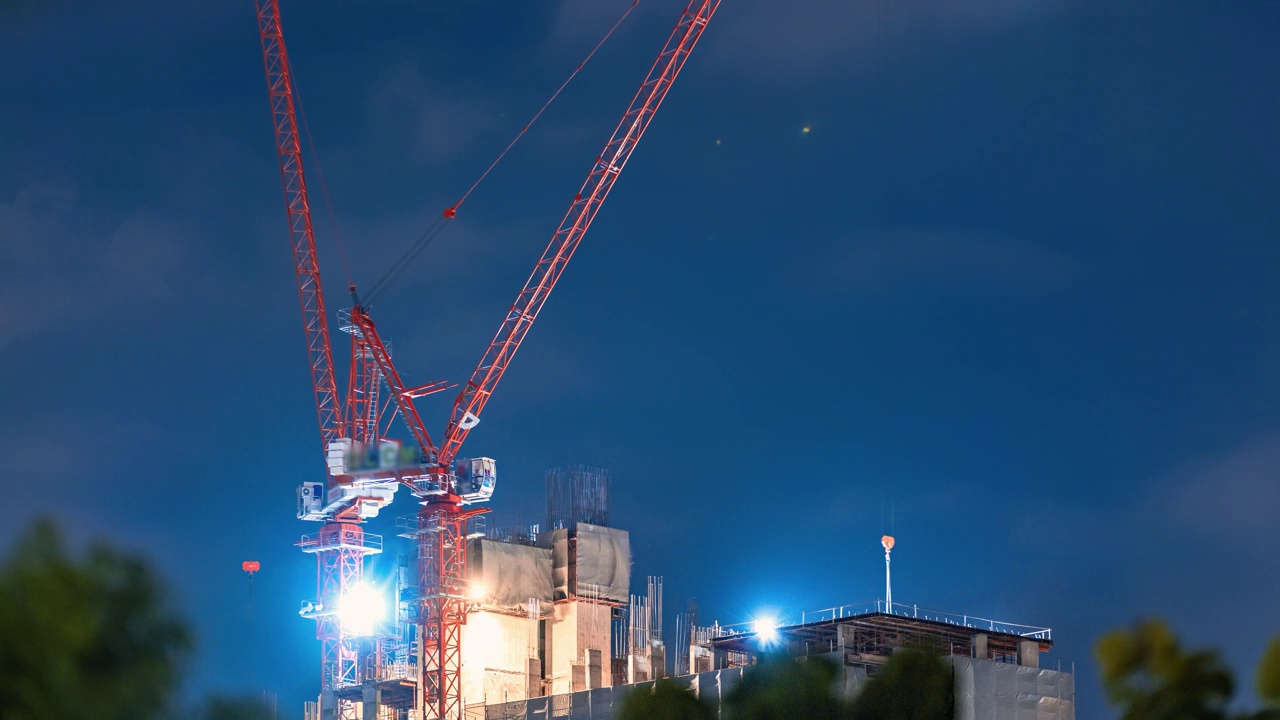 建筑起重机的时间流逝，建筑工人在雨中工作的夜晚视频素材