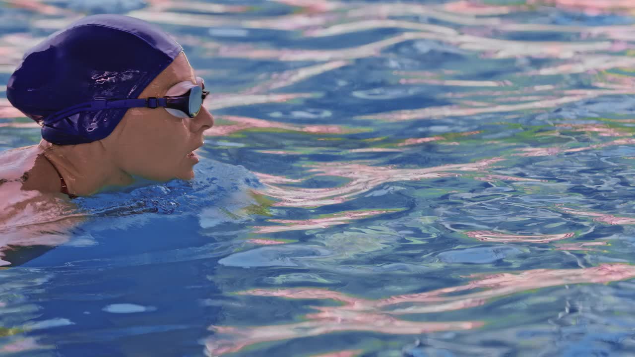 一名职业女游泳运动员在泳池边戴着护目镜的侧视图。一位女游泳者跳入水池。特写，慢镜头。视频下载