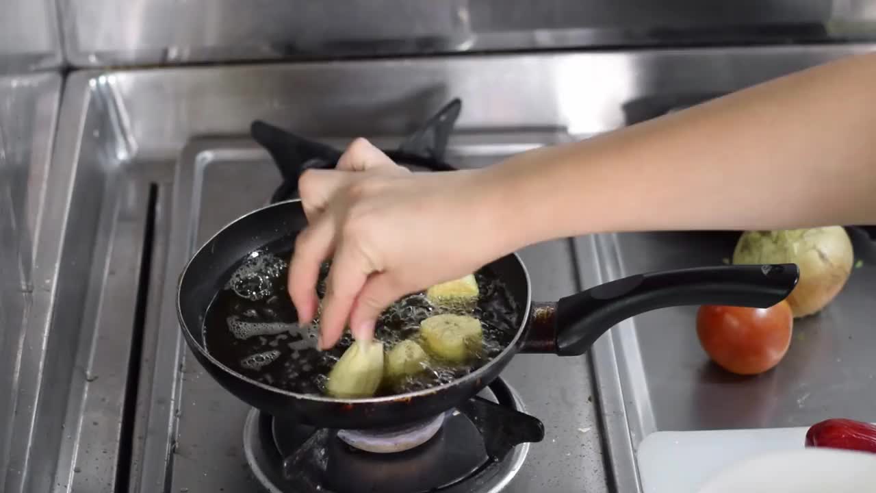 一个拉丁女人用手用植物油在煎锅里煎大蕉的Zenithal镜头。视频下载