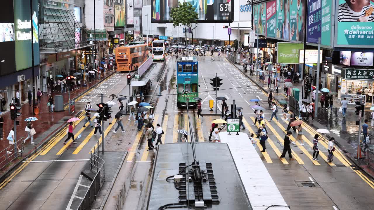 下雨天，香港铜锣湾购物区的中国人和亚洲游客走过斑马线。电车、公共汽车、汽车等交通工具。亚洲交通城市生活，香港旅游视频素材