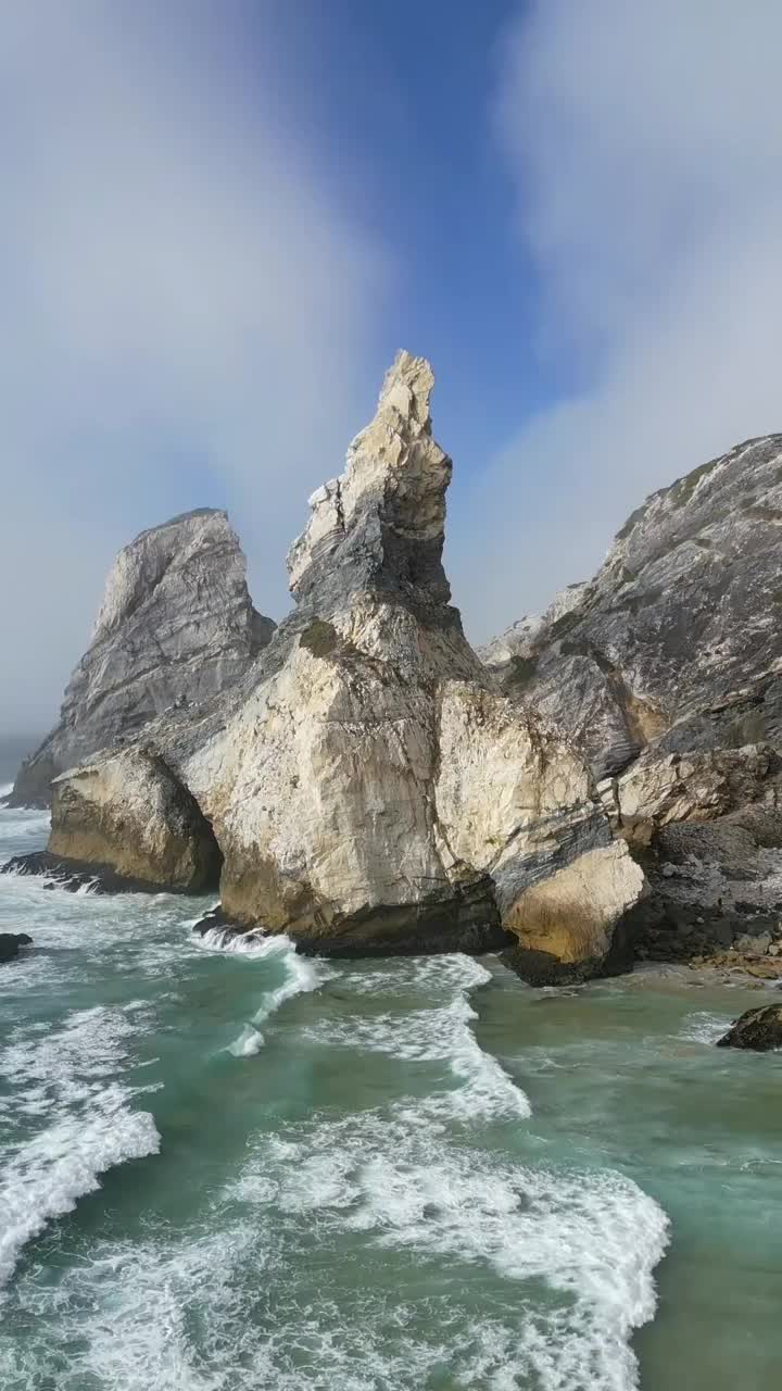 无人机垂直拍摄的大熊海滩岩层与海浪和蓝色多云的天空视频素材