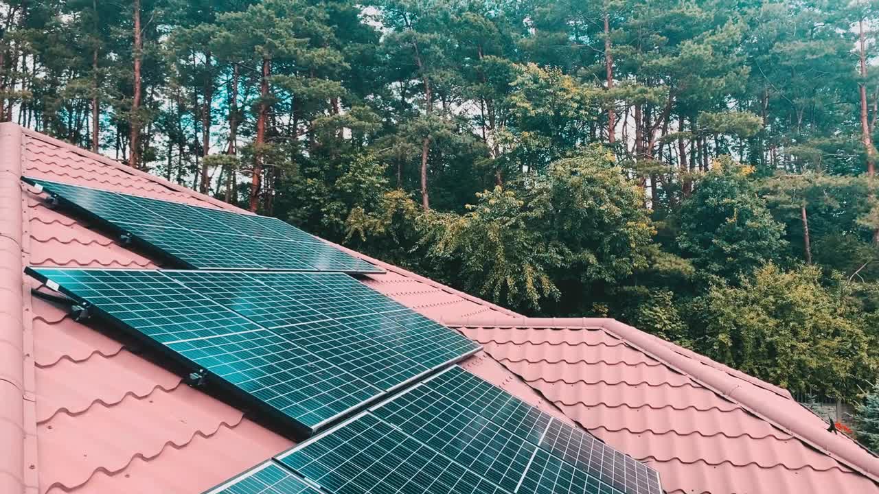 屋顶上的太阳能板和背景上的树木|可再生能源的生态解决方案视频下载