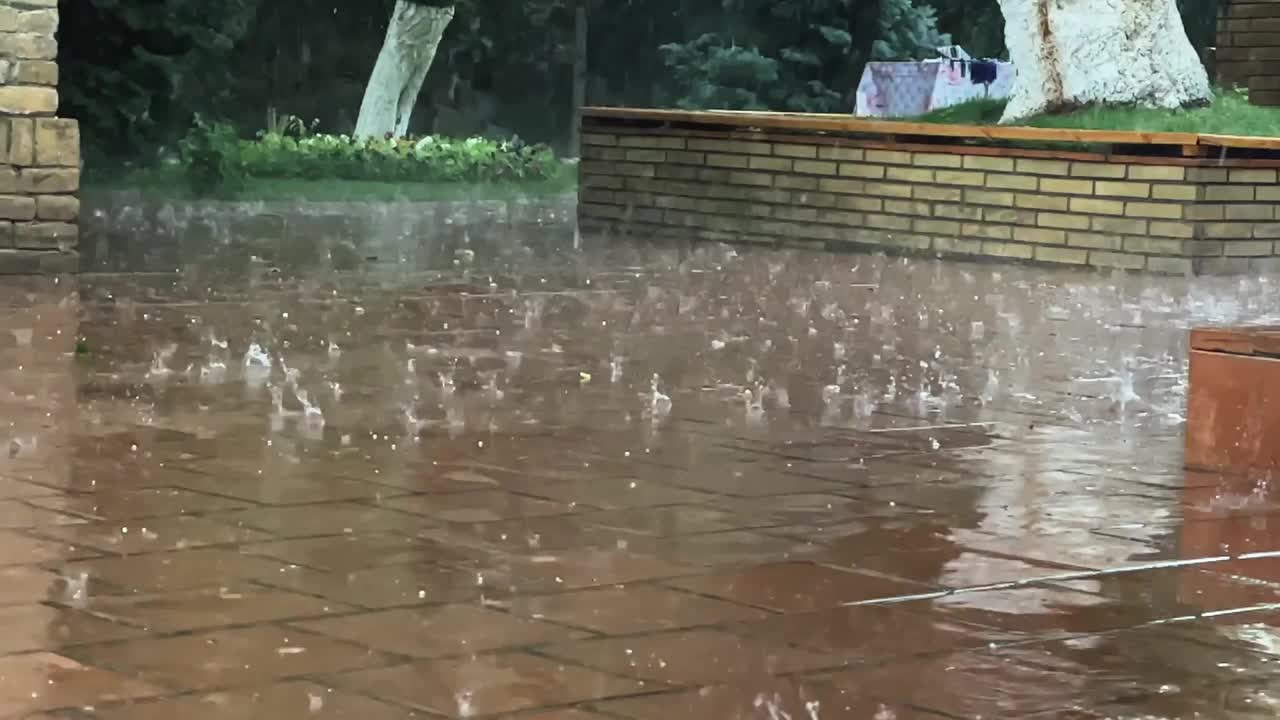 夹杂着冰雹的大雨点落在石板上。慢动作视频。视频素材