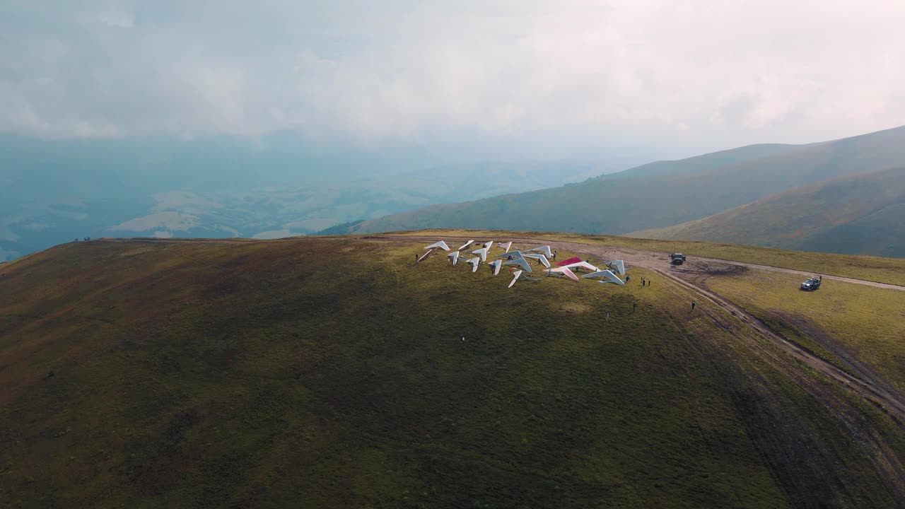 一群悬挂式滑翔机在山顶准备起飞视频下载