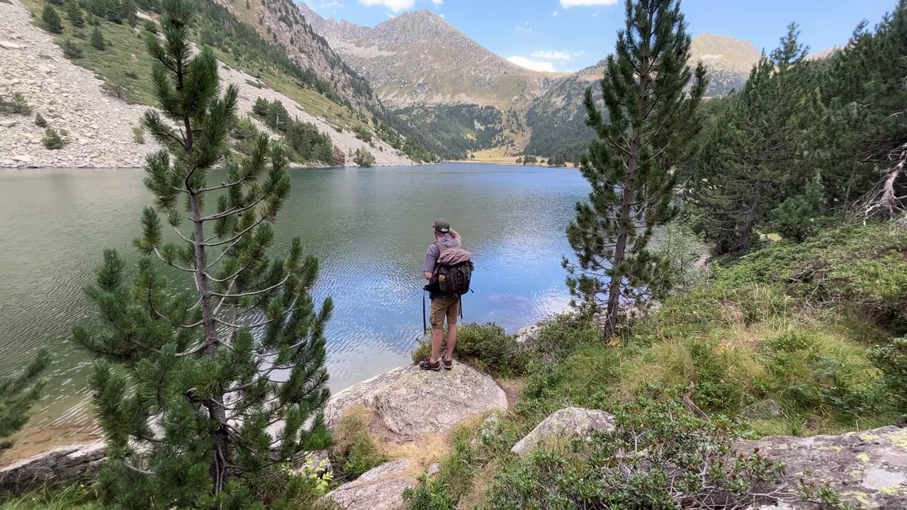 一名男子夏天在湖边的高山森林里徒步旅行视频素材