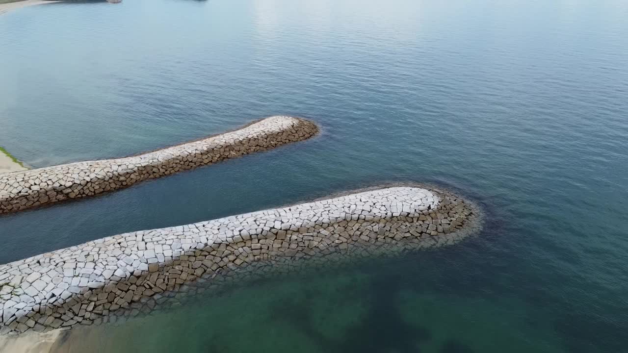 无人机拍摄的海滩附近有石头屏障的大海和有山的建筑视频素材