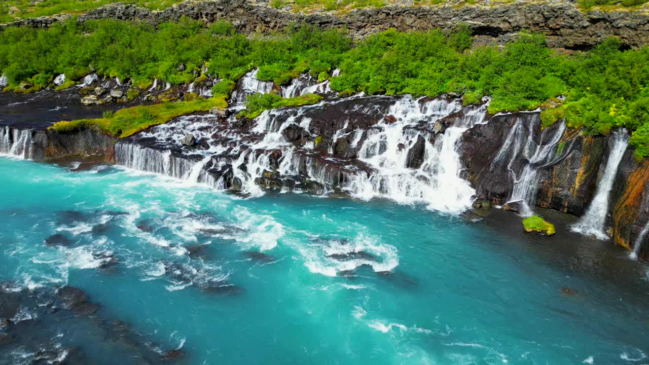 冰岛Hraunfossar瀑布与绿色山丘景观的鸟瞰图视频素材