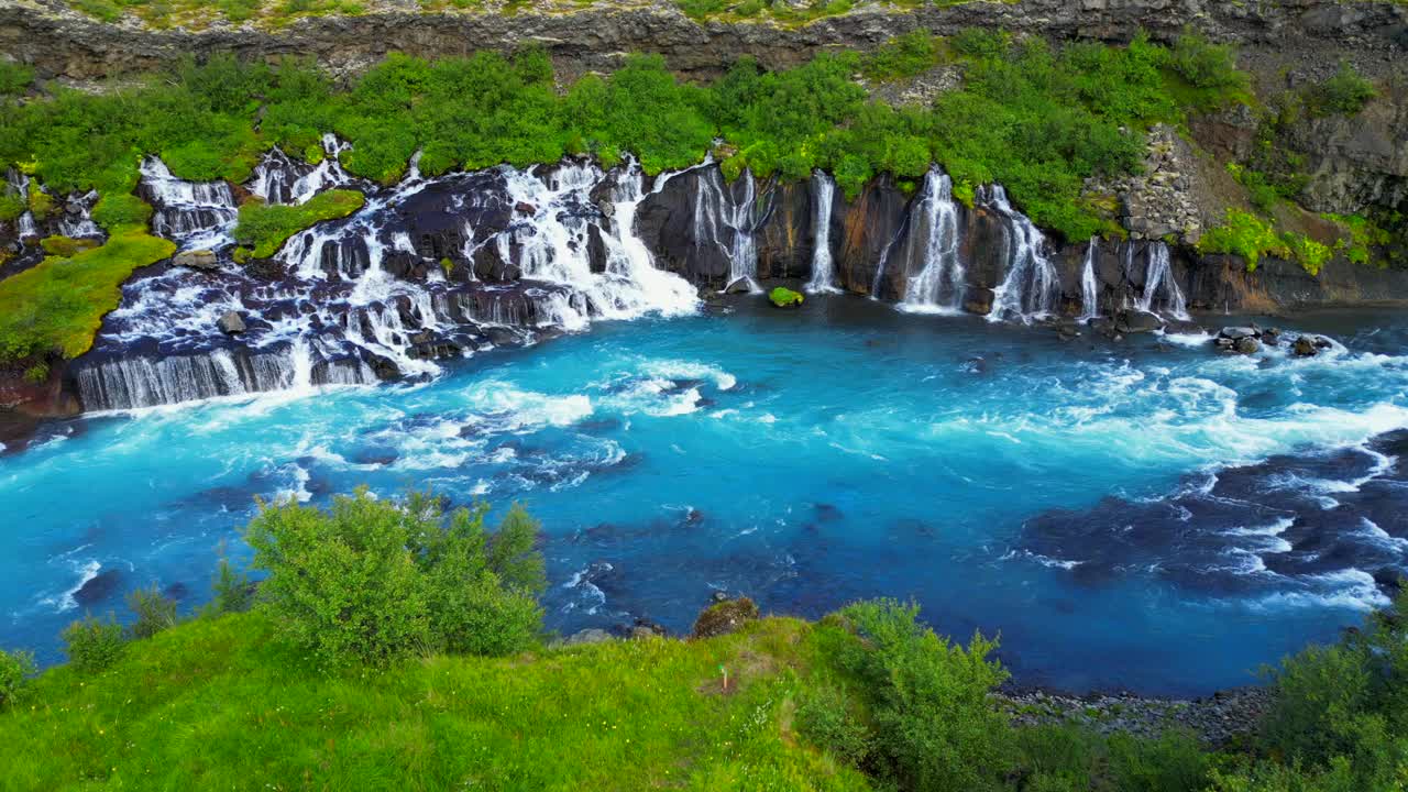 冰岛Hraunfossar瀑布与绿色山丘的鸟瞰图视频素材