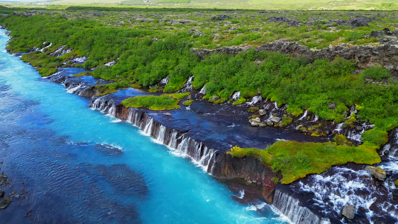 冰岛Hraunfossar瀑布与绿色山丘的无人机景观视图视频素材