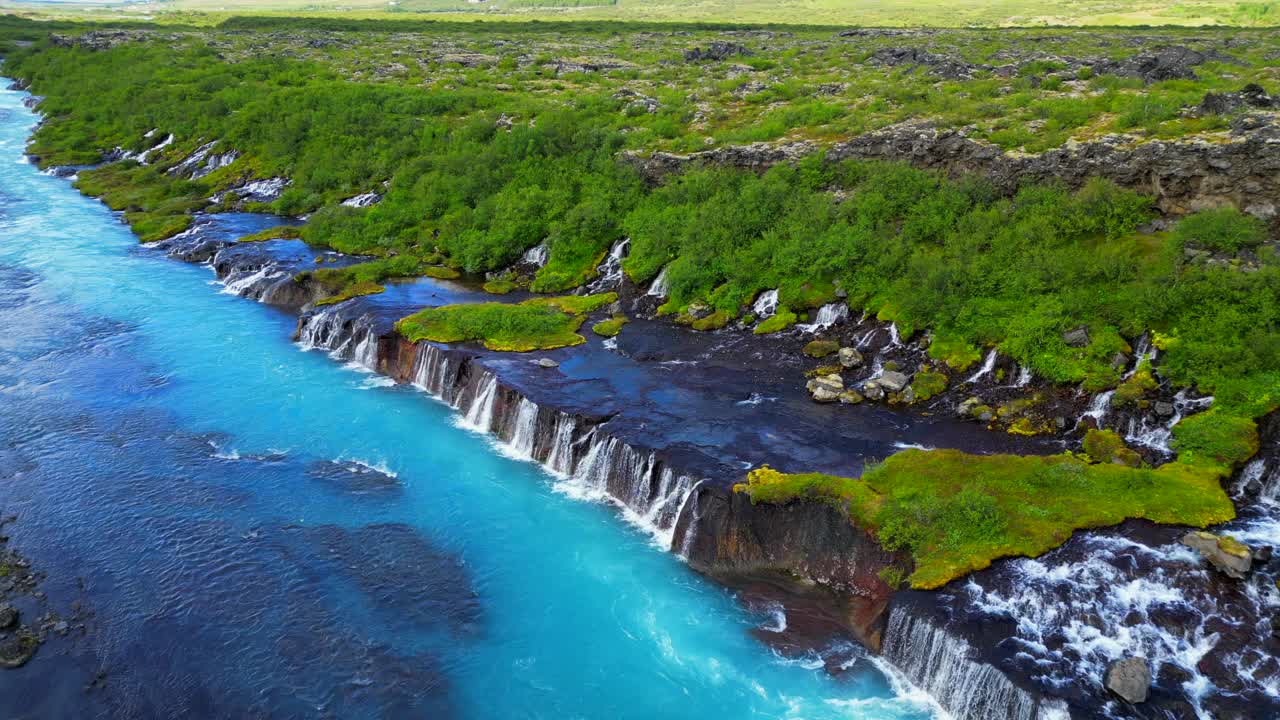 无人机拍摄的冰岛Hraunfossar瀑布景观和绿色的山丘视频素材