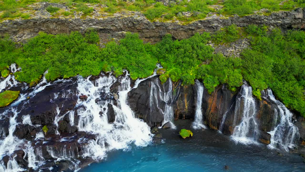 冰岛的Hraunfossar瀑布与绿色山丘的美丽无人机视图视频素材