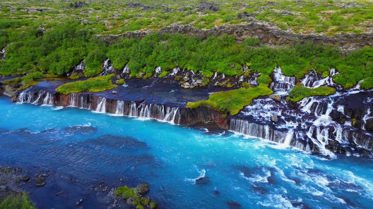 冰岛Hraunfossar瀑布景观与绿色山丘的鸟瞰图视频素材