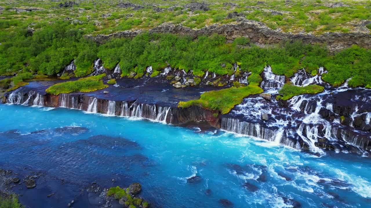 冰岛Hraunfossar瀑布景观与绿色山丘的鸟瞰图视频素材