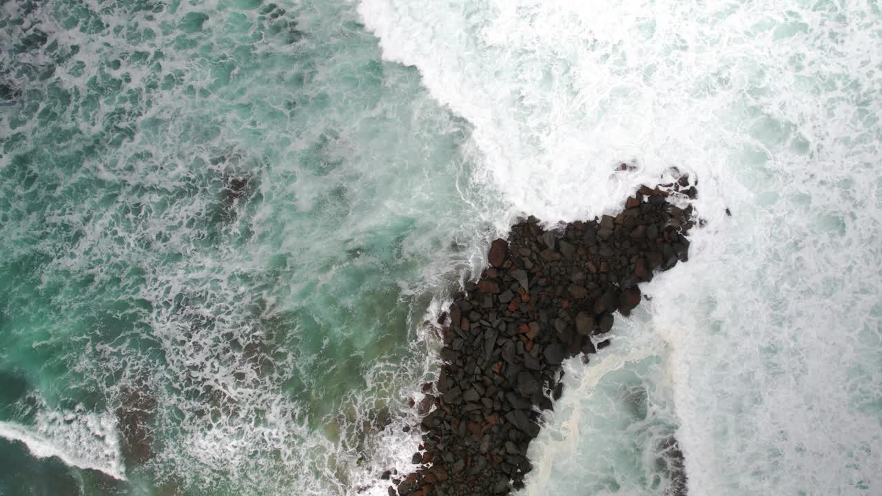 空中无人机拍摄的蓝绿色海浪撞击岩石的画面视频素材