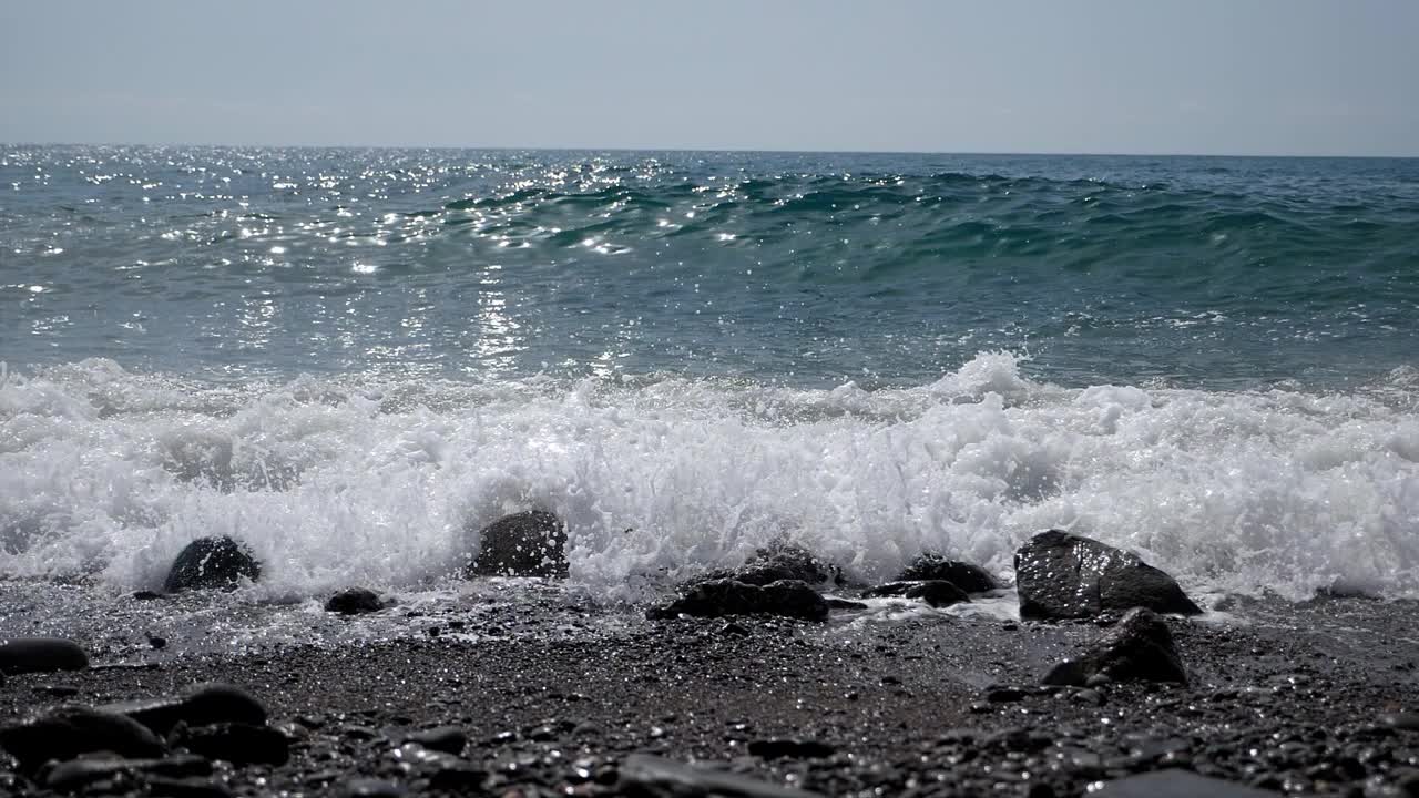 巨大的海浪在岸边的鹅卵石上击碎泡沫的惊人景色。视频素材