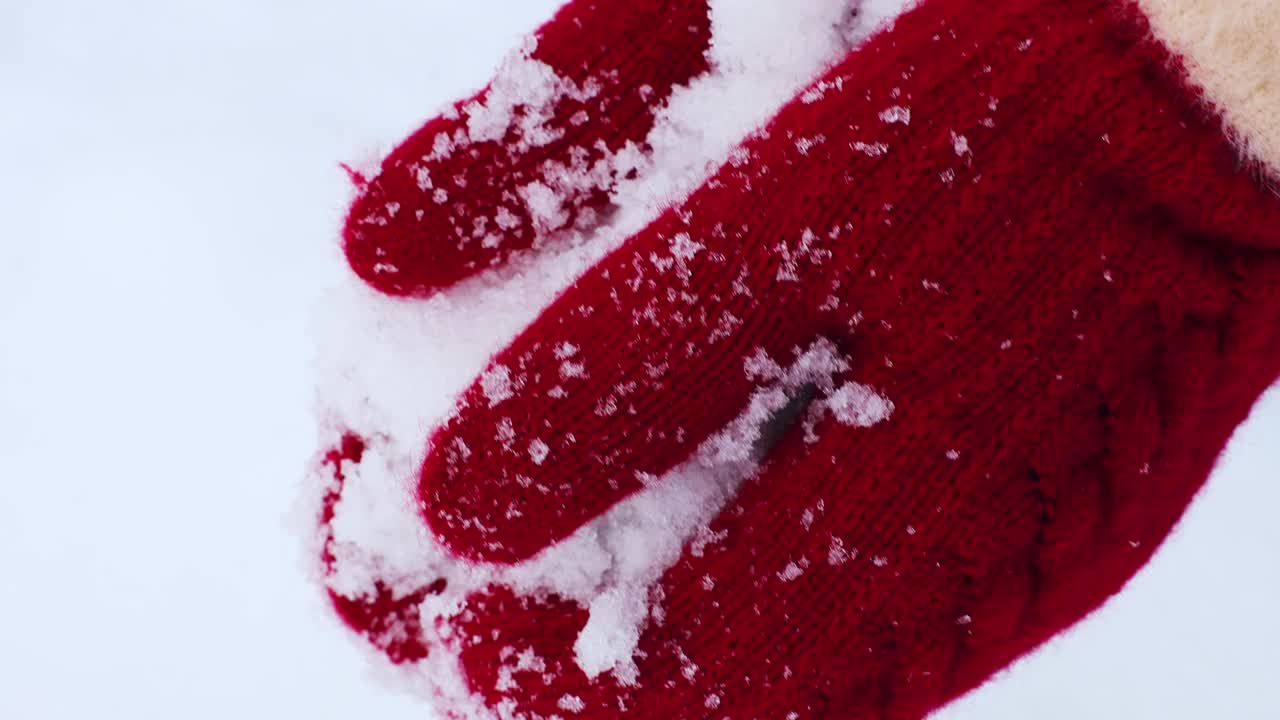 冬天，女人戴着红色针织连指手套，手里拿着雪。近距离观察，只有手，没有人情味视频素材