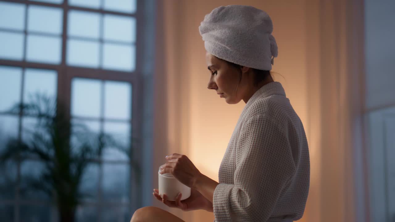 华丽的女人保湿腿在浴室的特写。女士在晚上抹面霜视频素材