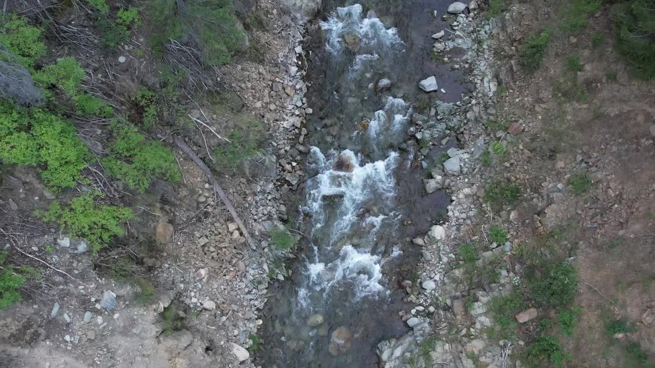 鸟瞰图狭窄的水流和小瀑布之间的岩石和树木视频素材