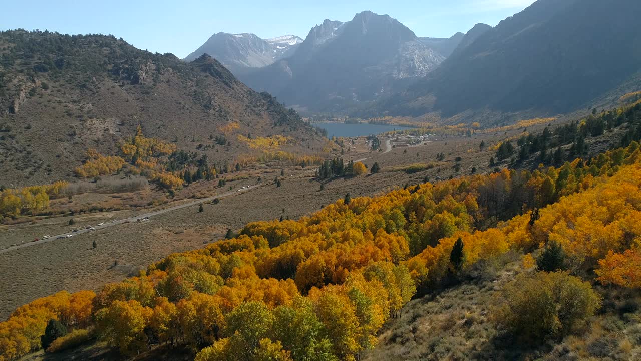 在阳光明媚的日子里，无人机在景观上空飞行，覆盖着秋天树木的山的航拍照片-猛犸湖，加利福尼亚视频素材