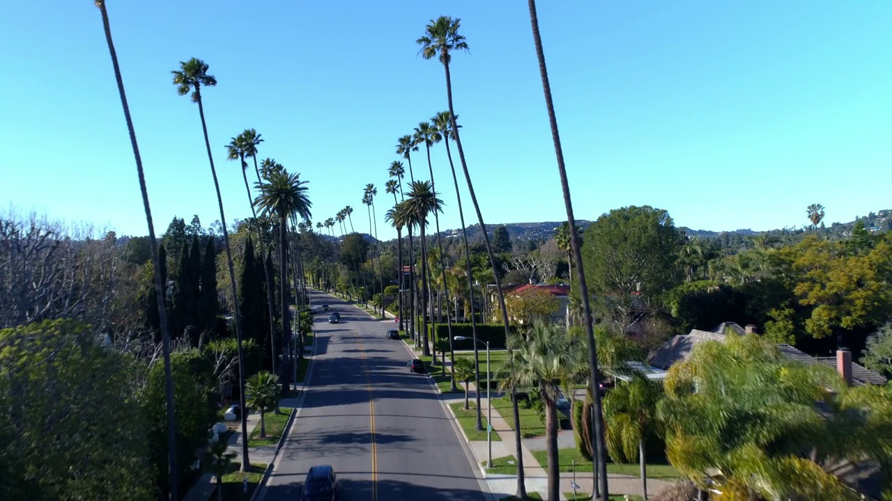 天空湛蓝的洛杉矶市，道路上树木和房屋间的车辆的空中上升远景视频素材