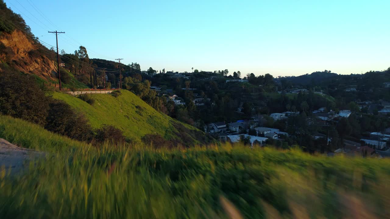 空中向前拍摄的道路在山上附近的房子与树木和植物对天空在日落-洛杉矶，加利福尼亚视频素材