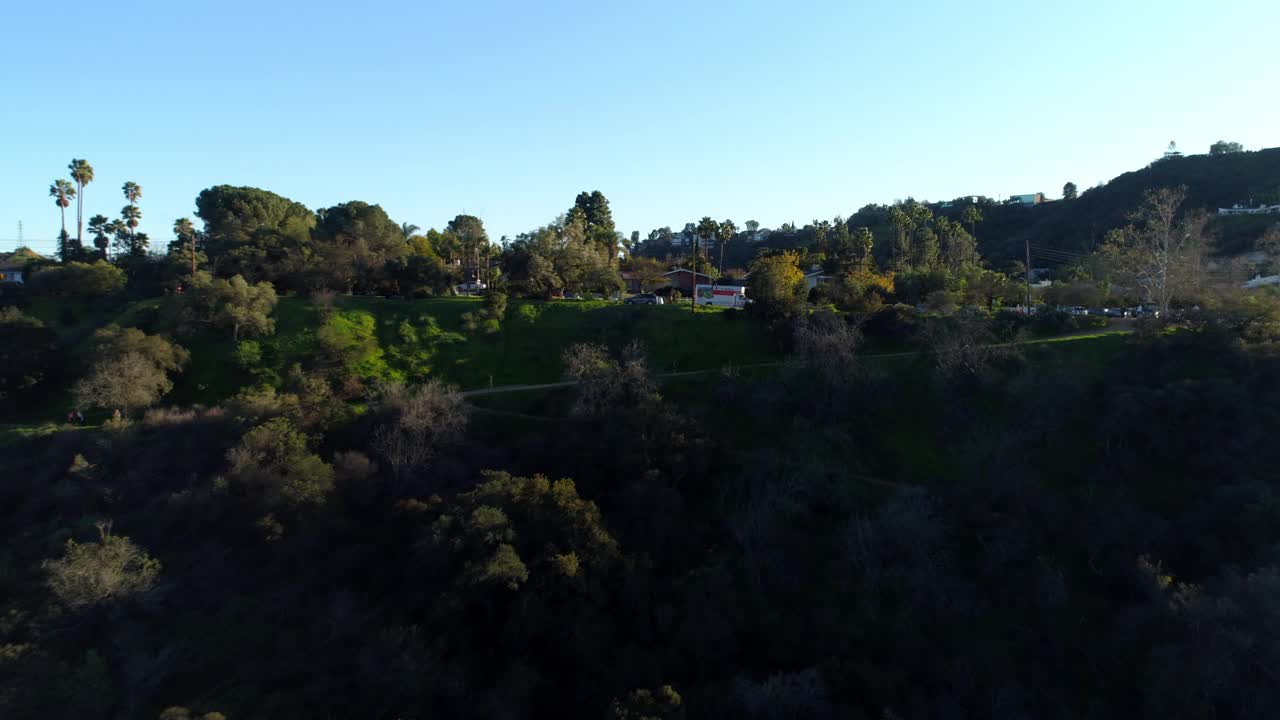 空中向后拍摄的房屋和车辆在树木和植物在山上对蓝天-洛杉矶，加利福尼亚视频素材