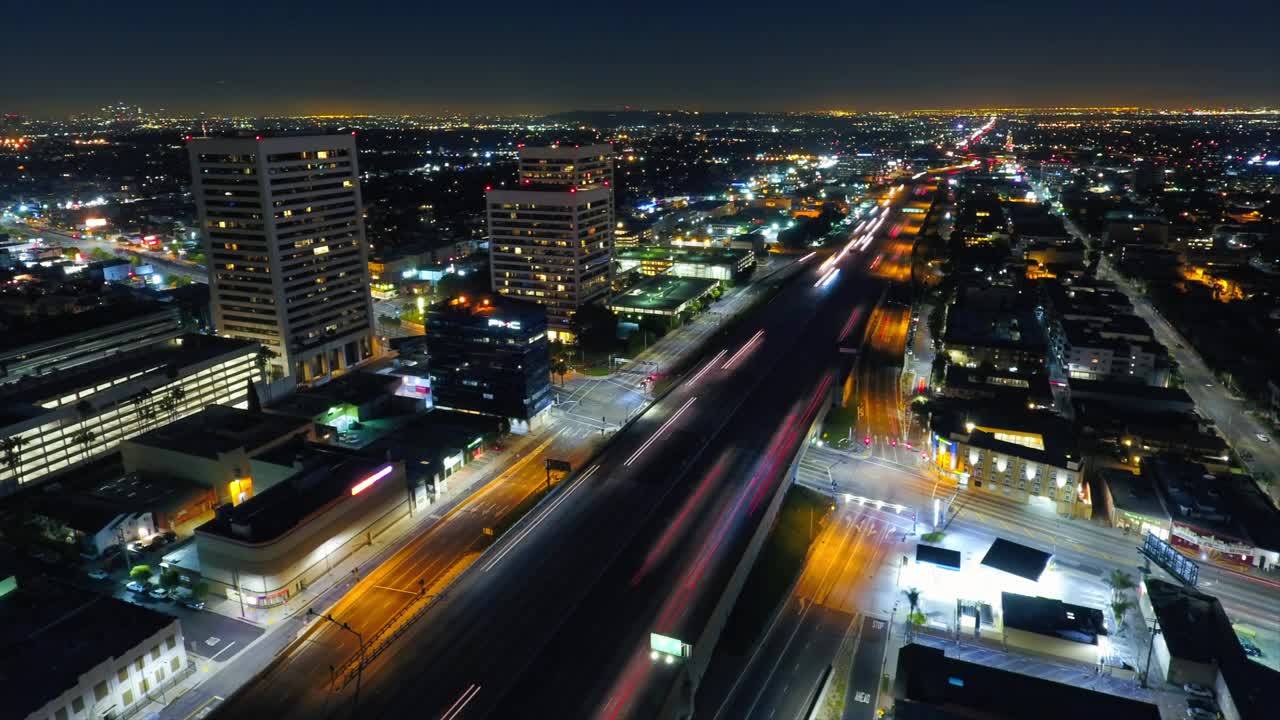 夜间在城市建筑物旁的道路上的汽车的空中锁定延时拍摄-洛杉矶，加利福尼亚视频素材