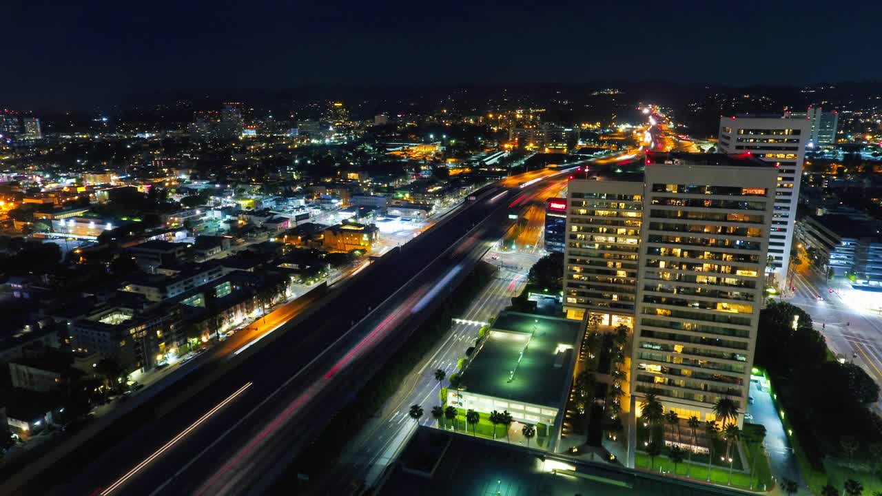 夜间城市建筑物间道路上的灯光轨迹的空中锁定延时拍摄-洛杉矶，加利福尼亚视频素材