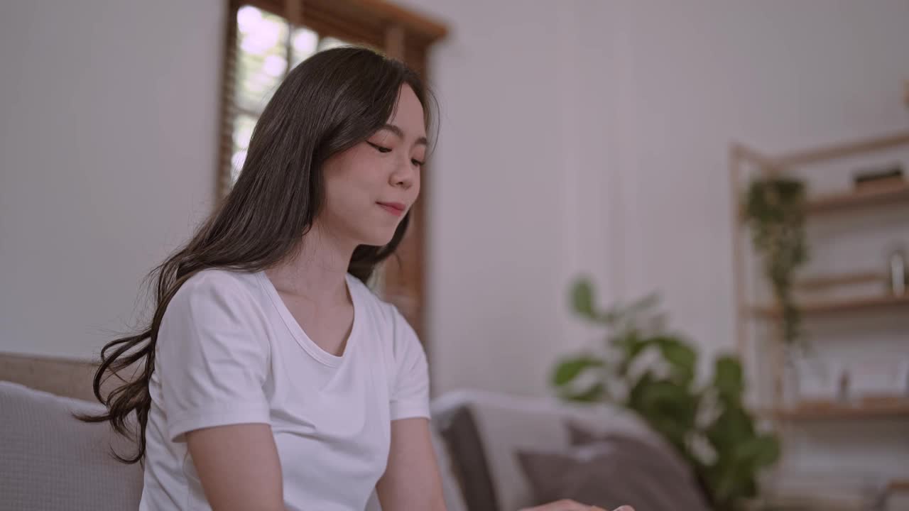 年轻饥饿的亚洲妇女吃着垃圾食品汉堡包，在家里吃着快餐，展示着减肥食品的选择。视频素材
