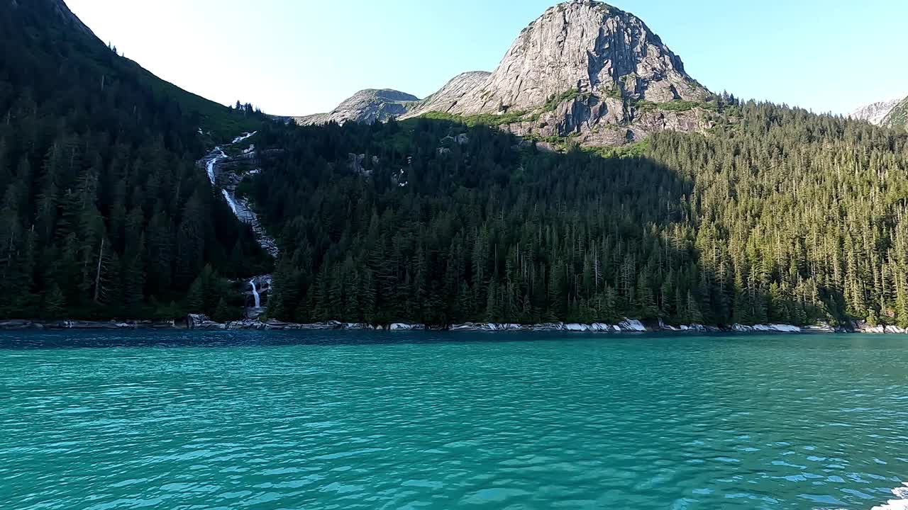 一个美丽的瀑布的水，在森林中央流动，流入大海。大松树和绿松石水在这个视频中脱颖而出。视频下载