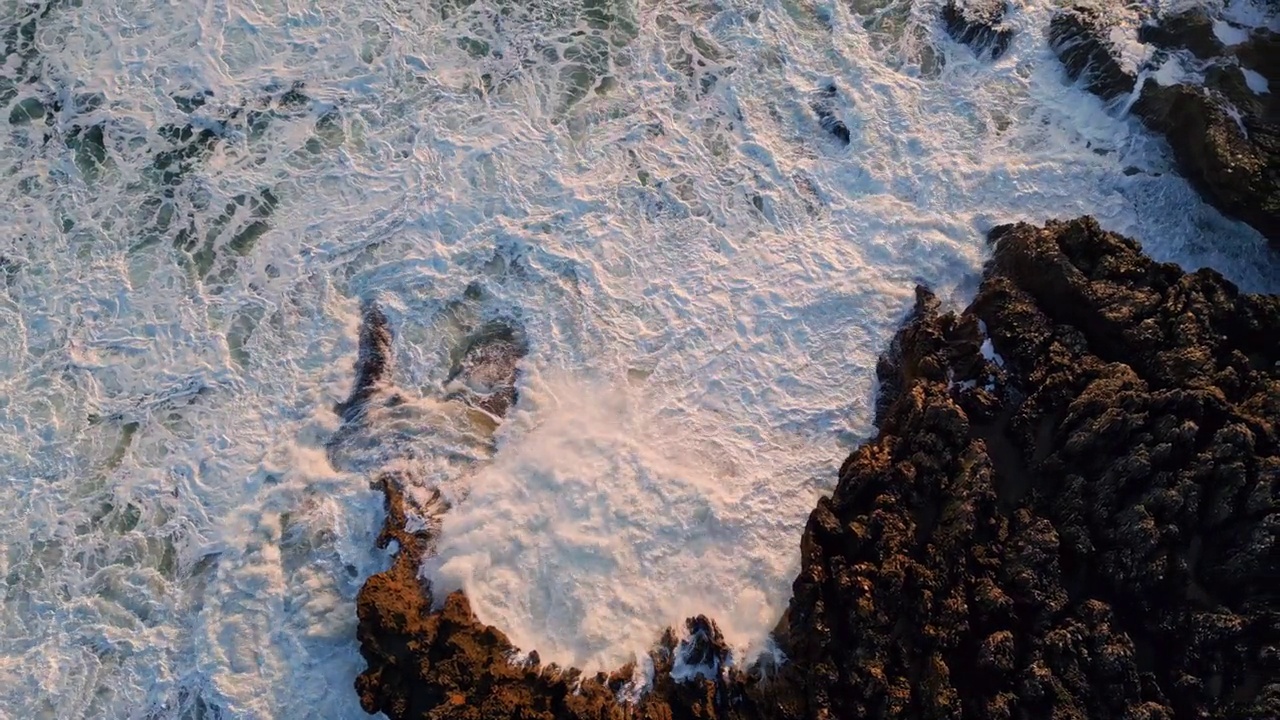 鸟瞰图暴风雨般的海浪打碎了火山岩。水流景观视频素材