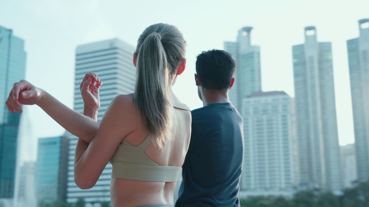亚洲年轻夫妇穿着运动服，早上一起慢跑后伸展身体的特写。视频素材