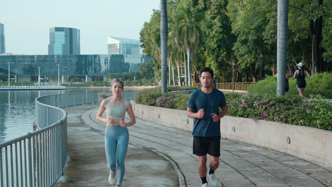 亚洲年轻夫妇穿着运动服在公园晨跑锻炼的肖像。视频素材
