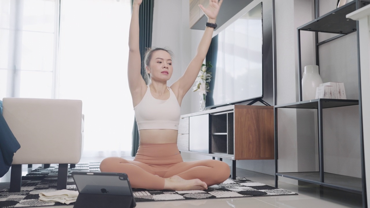 美丽的成年亚洲妇女练习瑜伽和伸展运动在家里视频素材