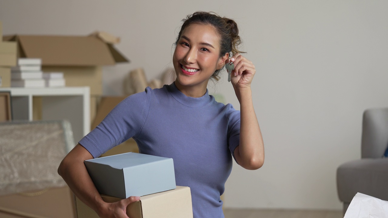 快乐的年轻亚洲女人展示新房子的钥匙。视频素材