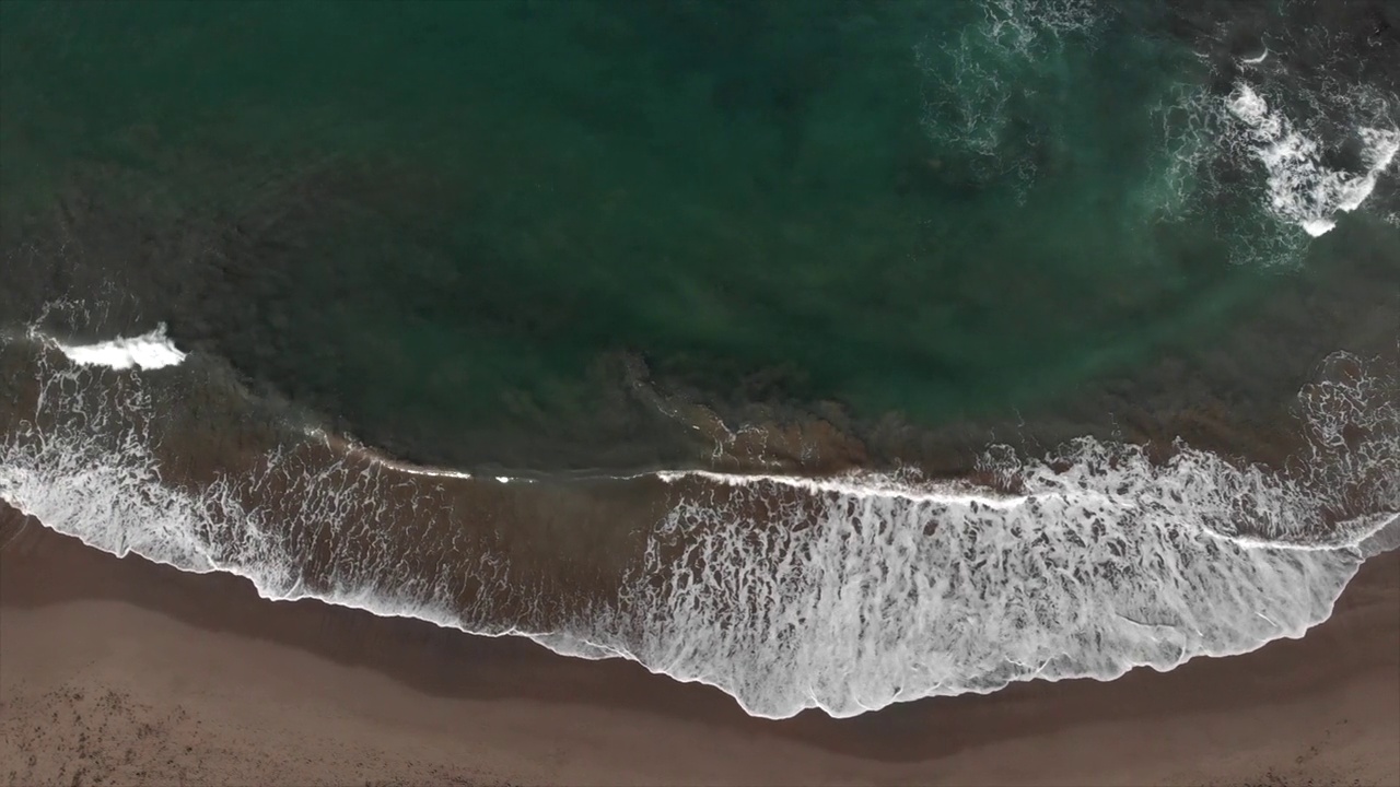 航拍的海浪在沙滩的海岸线上飞溅。无人机沿着海浪翻滚到美丽的海滩。抽象自然背景旅行。4 k视频素材