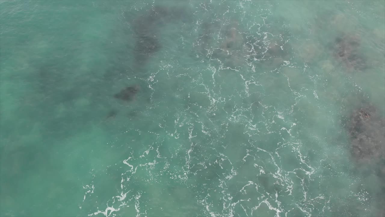 鸟瞰图海浪飞溅白色泡沫在阳光明媚的日子。波浪在水面上翻滚的俯视图。美丽的大自然和旅游暑假的概念。视频素材