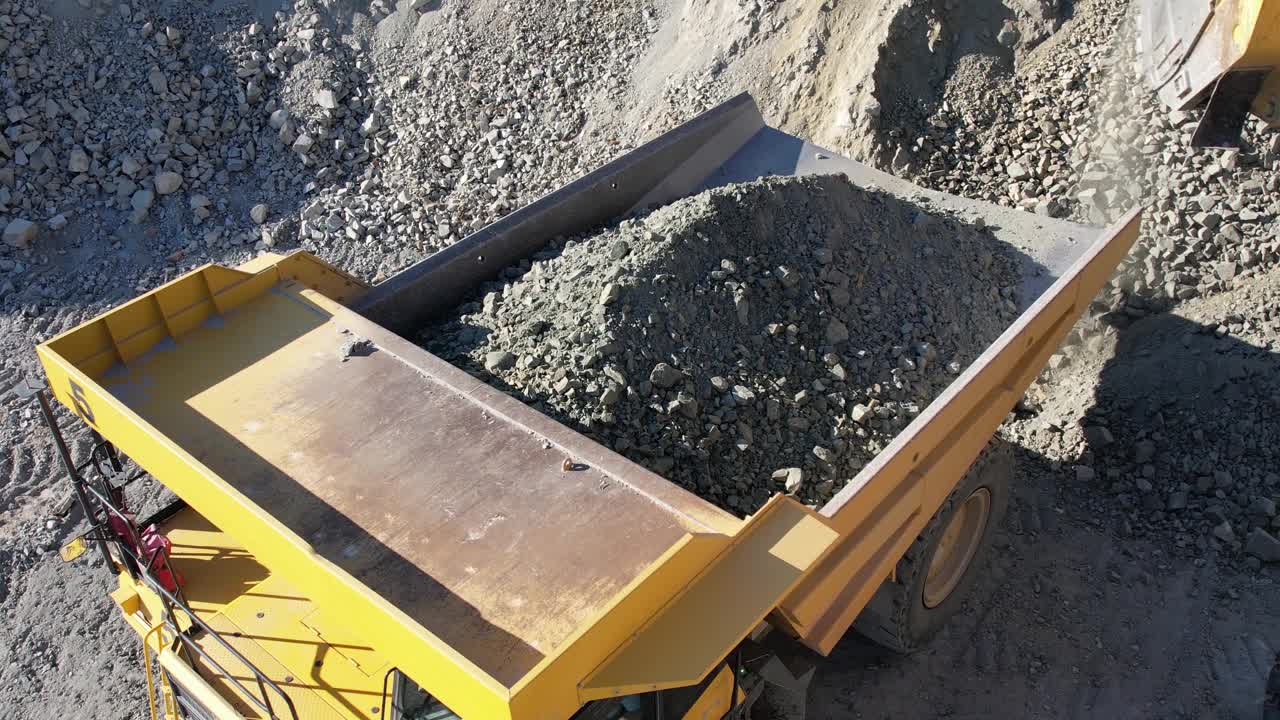 在碎石采石场，挖掘机将碎石装入自卸卡车，慢动作视频素材