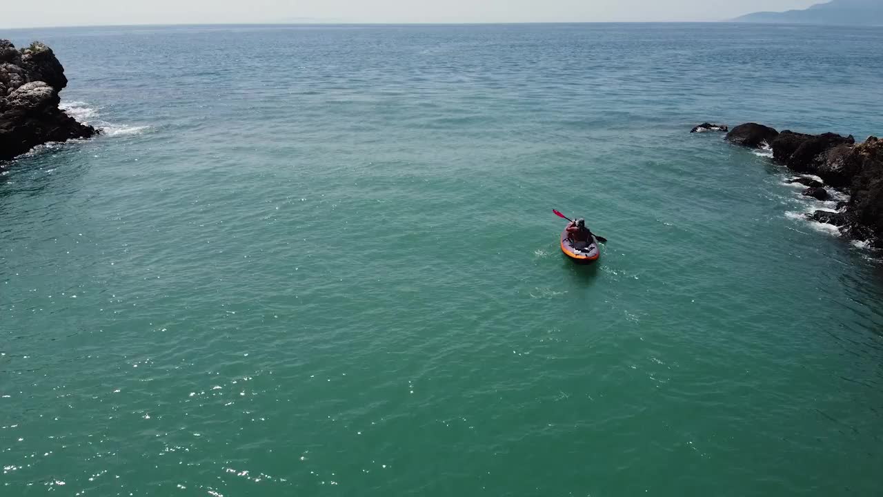 在碧绿的海水中划着皮艇的男子视频素材