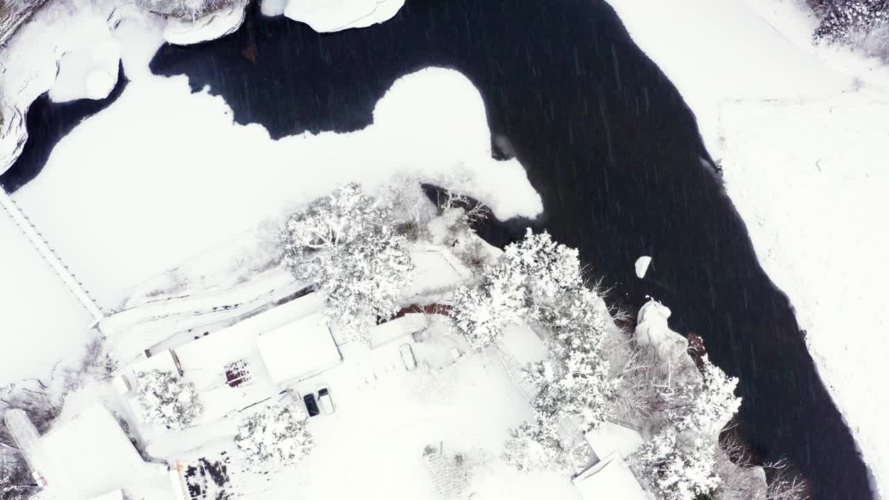下雪天小村庄和山间河流鸟瞰图。视频素材