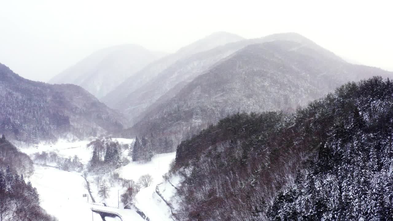 下雪天小村庄和山间河流鸟瞰图。视频素材
