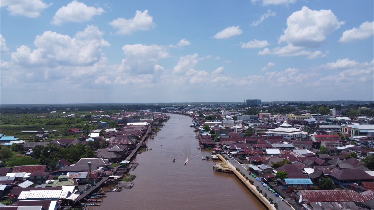 城市在河岸上的鸟瞰图，船只在河上飞驰。Pangkalan Bun，加里曼丹中部，印度尼西亚- 2023年8月25日视频素材