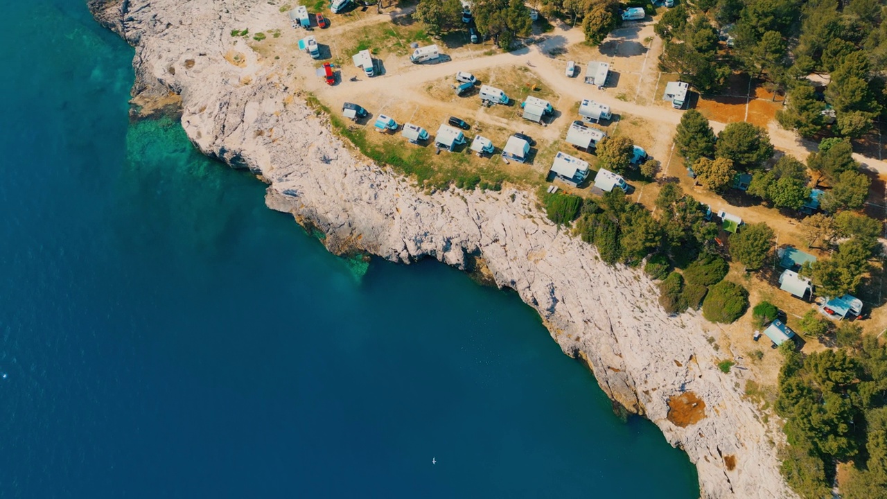 夏日里，露营拖车停在蓝海附近的岩石岸边视频素材