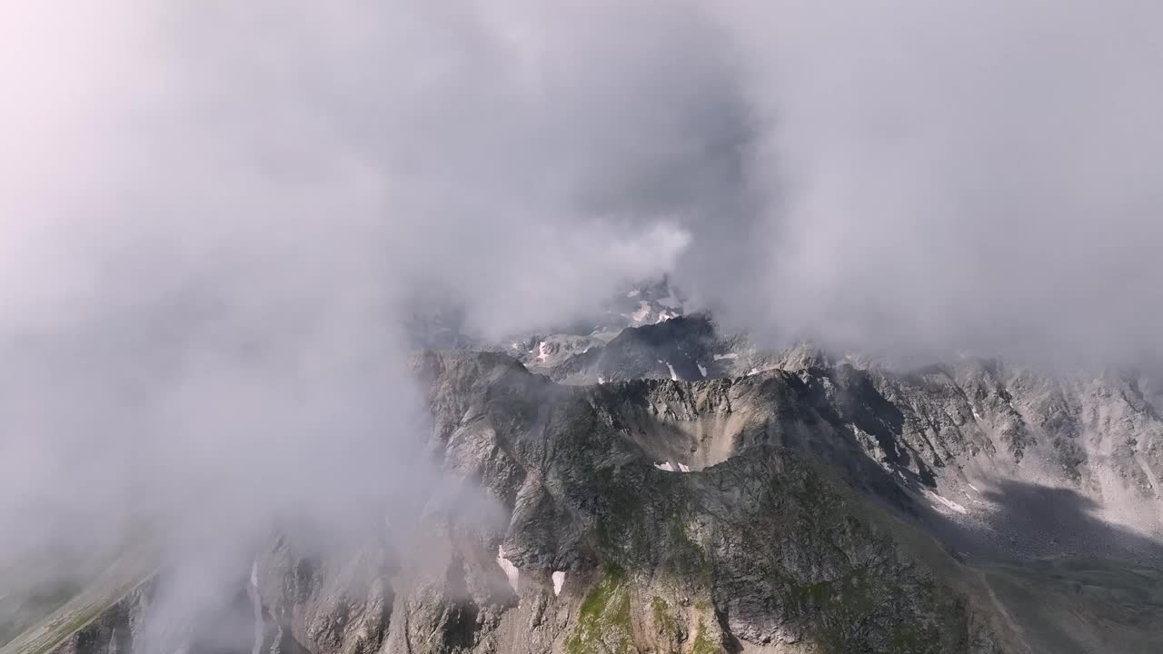 山脉从下面的云层中飞过。低云覆盖下的空中飞行。天气变化，全球变暖。鸟瞰图视频素材