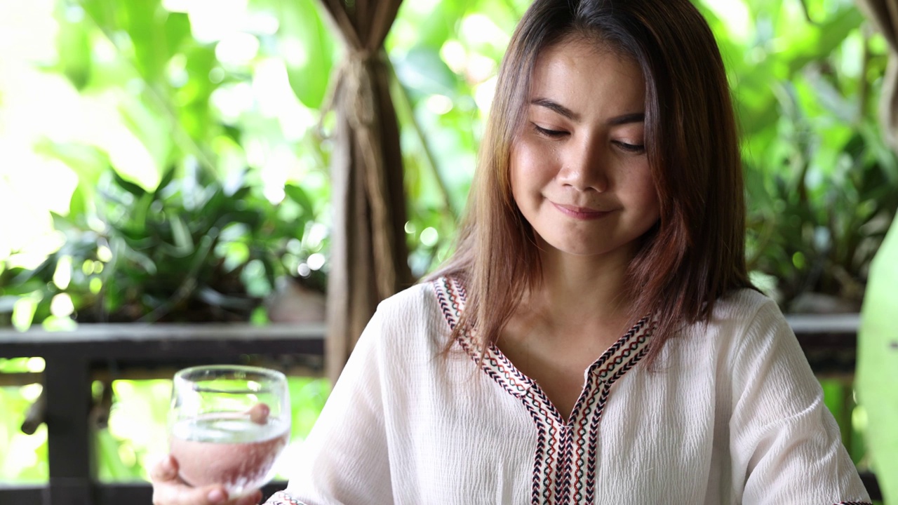 一个亚洲女人在餐馆里喝干净的水视频素材