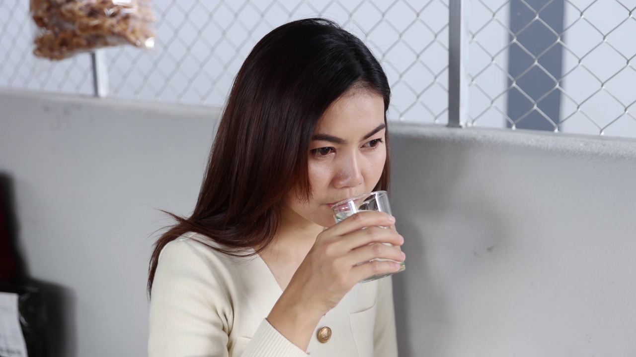 一个亚洲女人在餐馆里喝干净的水视频素材