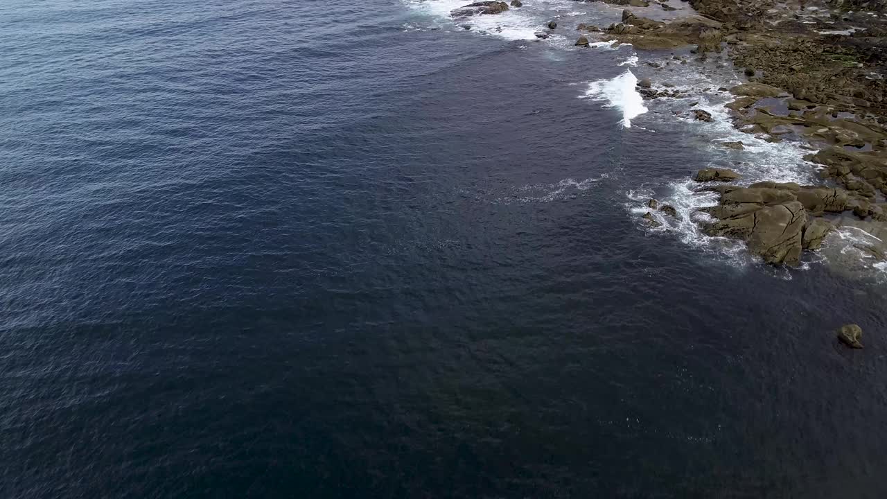 无人机在海上拍摄的画面，海浪拍打着海岸上的石头视频素材