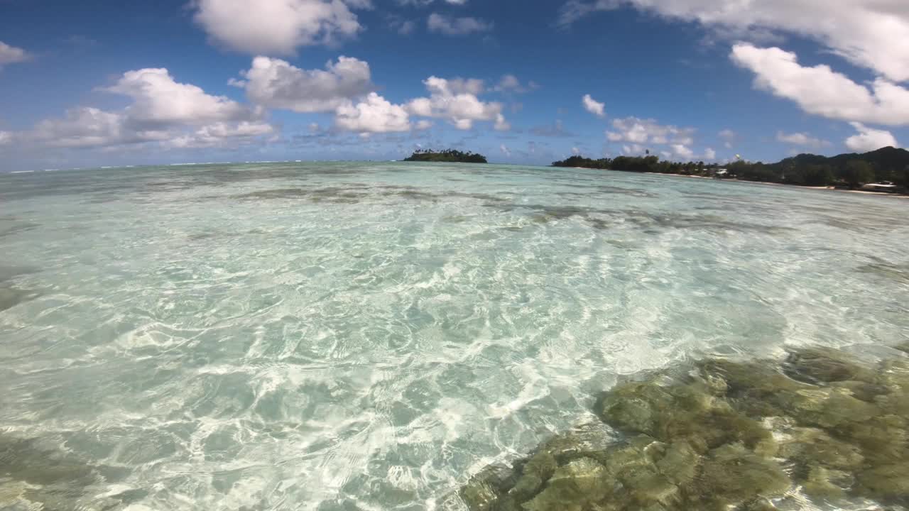 在清澈的绿松石湍流中醒来的广角视角，浅泻湖，咸海海水和沙质海床上有珊瑚礁和涟漪反射，向高冈岛的地平线望去视频素材