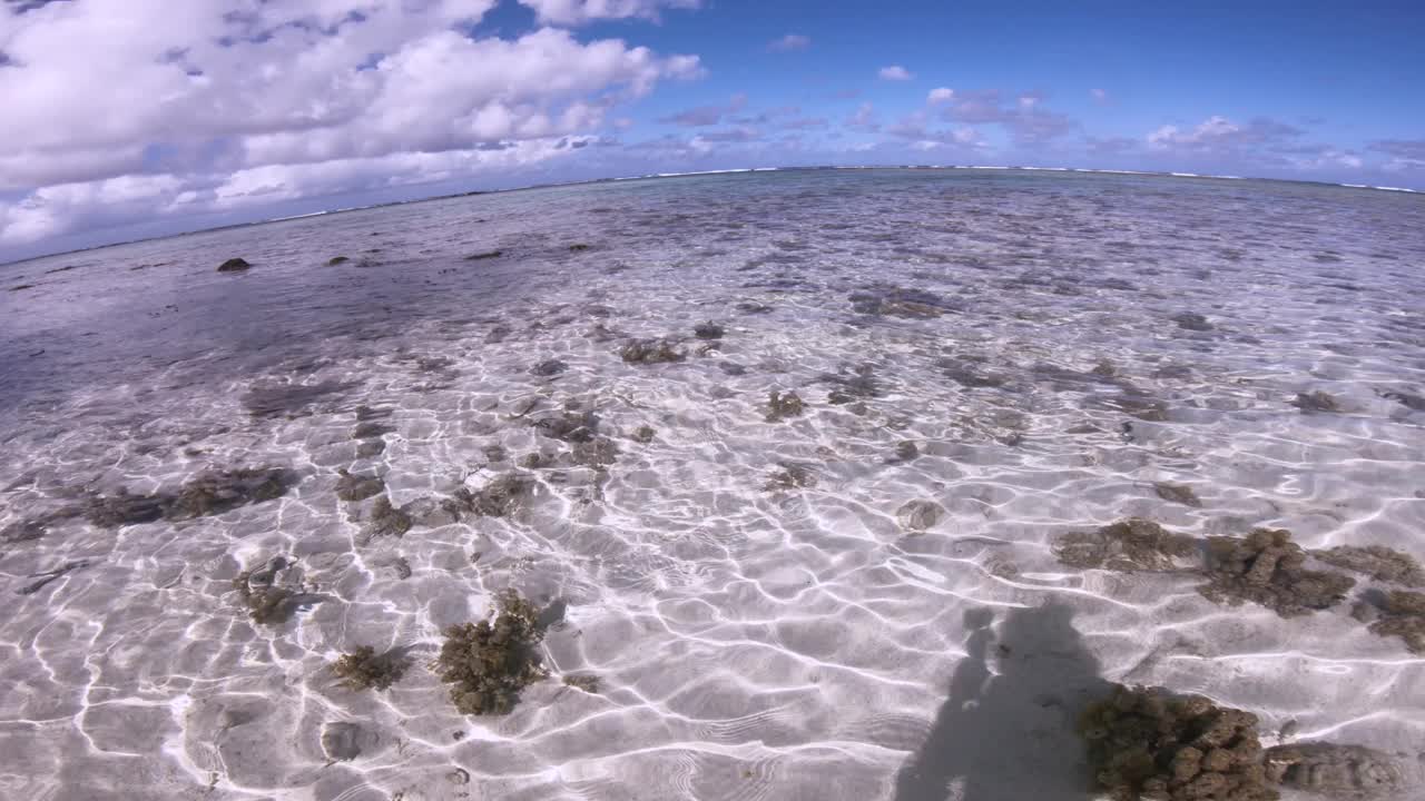 宽阔的视角，在清澈的绿松石蓝色浅泻湖咸海海水和沙质海床与珊瑚石和涟漪反射从Koromiri岛看向太平洋地平线视频素材